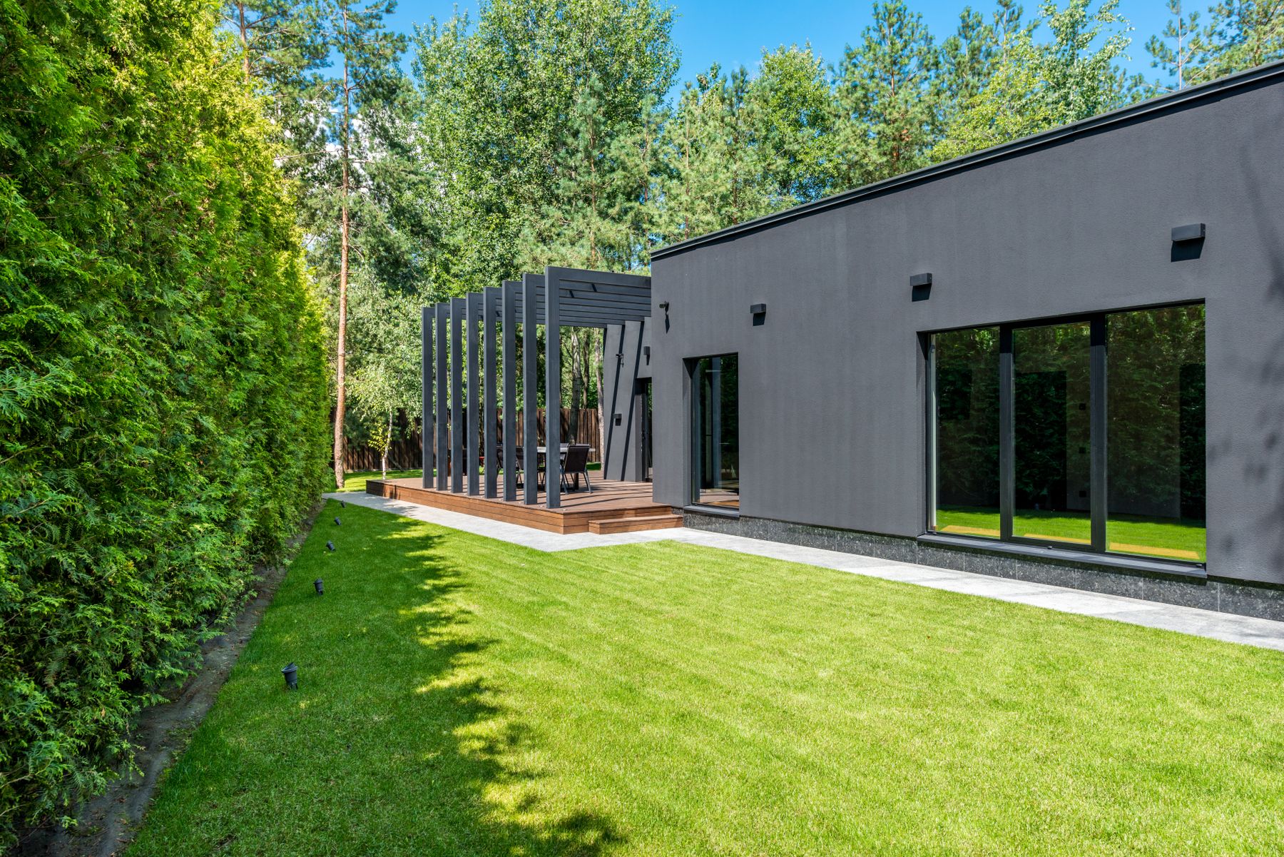 Illustrative garden with a lawn and timber terrace beside a contemporary home