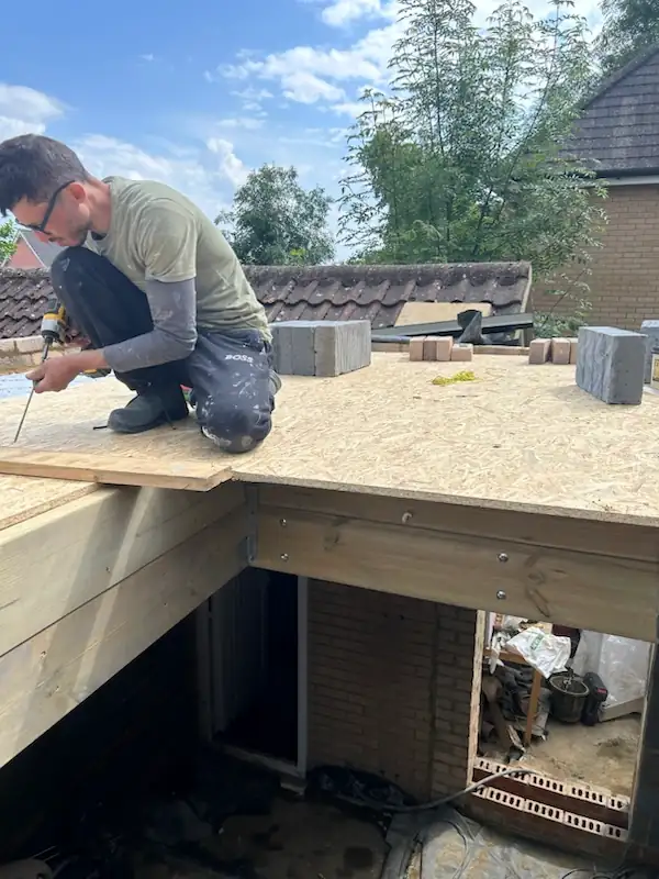 A TML Building team member fitting timber decking on an extension roof